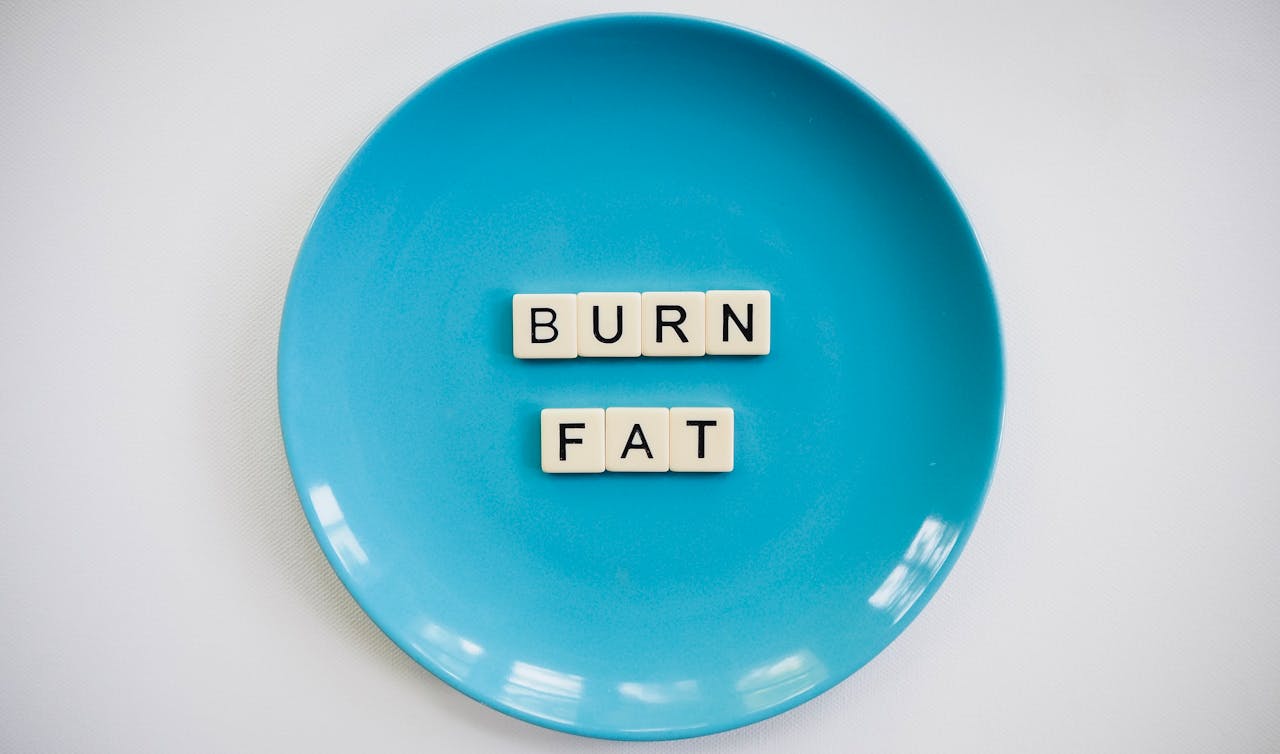 A conceptual image featuring the words 'Burn Fat' on a blue plate, symbolizing weight loss.